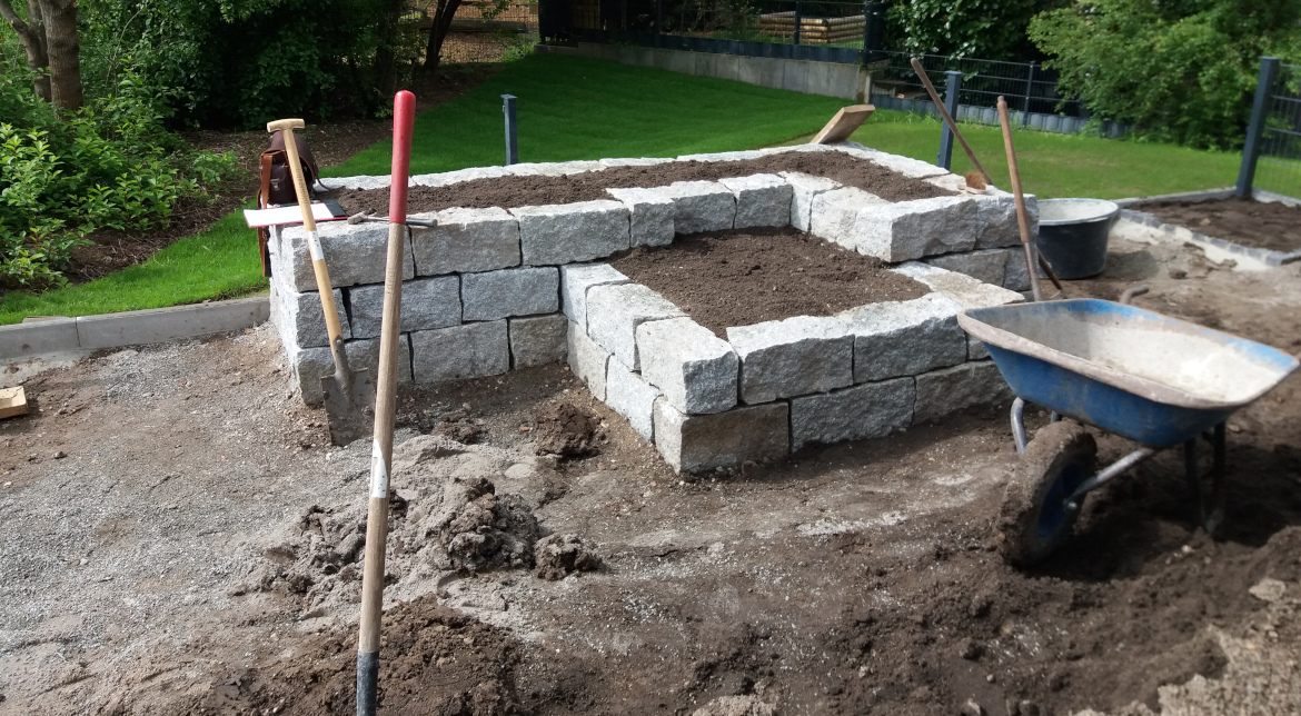 Trockenmauer-Hochbeet aus Granit-Mauersteinen in einem Hausgarten in Mannheim